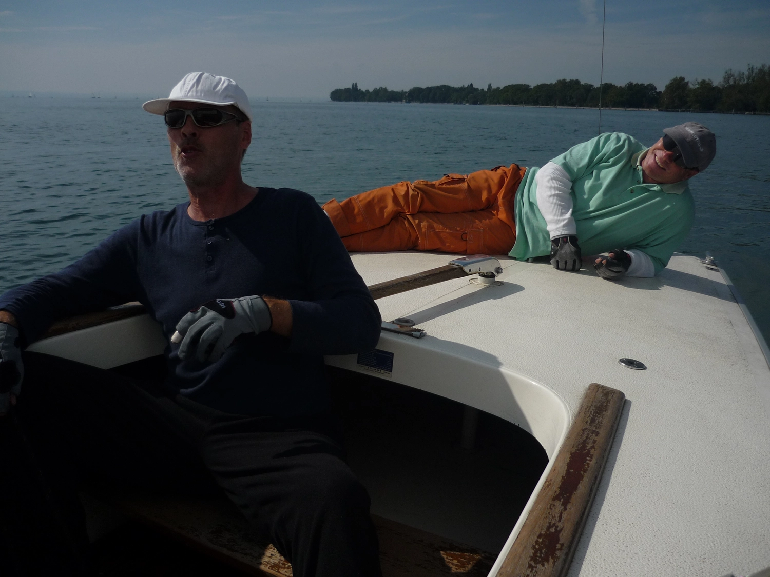 Motorboot-u. Segelschule Ravensburg - Wassersportausbildung und lizenzierung - Zwei Männer auf einem Segelboot; einer sitzt, während der andere auf dem Deck liegt.