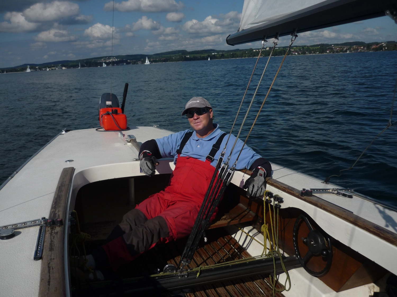 Motorboot-u. Segelschule Ravensburg - Wassersportausbildung und lizenzierung - Ein Mann, der eine Schwimmweste und eine rote Segelhose trägt, steuert ein kleines Boot über das offene Wasser.
