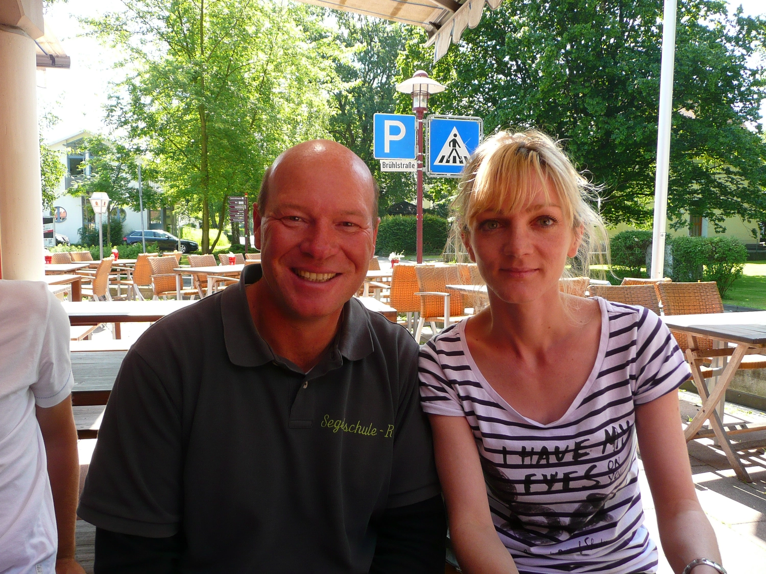 Motorboot-u. Segelschule Ravensburg - Wassersportausbildung und lizenzierung - Ein Mann und eine Frau lächeln gemeinsam in einem Straßencafé am Wasser.