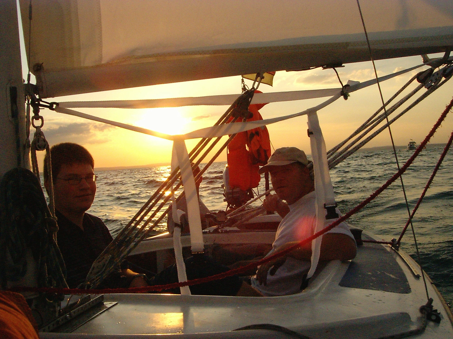 Motorboot-u. Segelschule Ravensburg - Wassersportausbildung und lizenzierung - Blick aus dem Inneren eines Segelboots auf zwei Personen während des Sonnenuntergangs.
