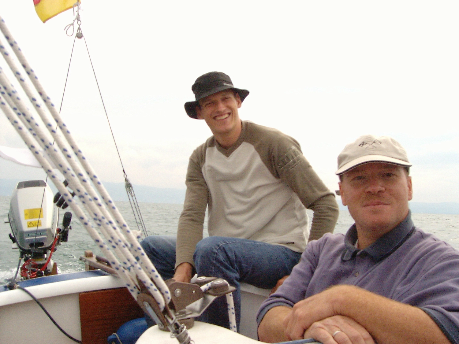 Motorboot-u. Segelschule Ravensburg - Wassersportausbildung und lizenzierung - Zwei Männer sitzen auf einem Boot, einer trägt einen Sonnenhut, der andere eine Baseballkappe.