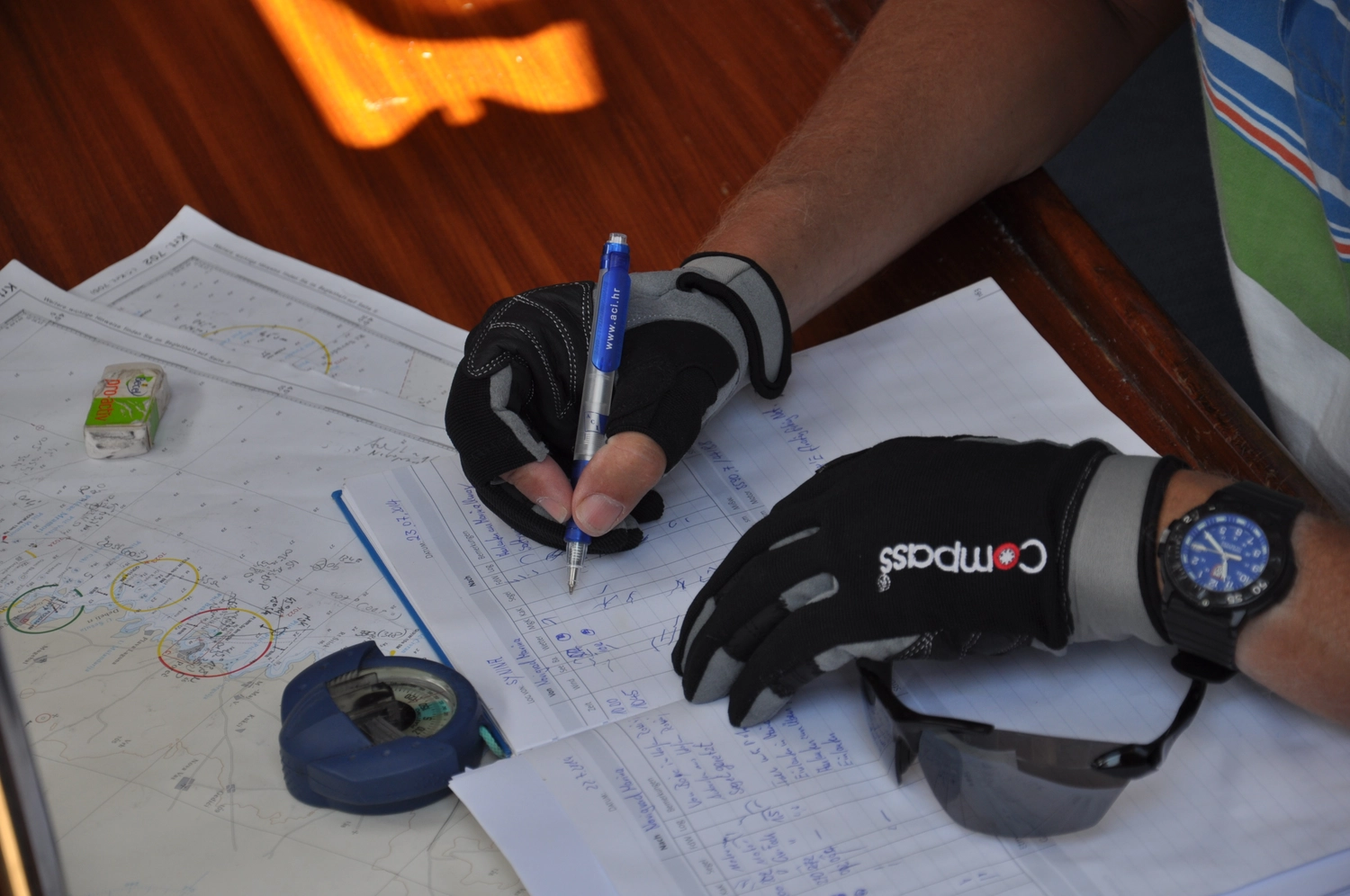 Motorboot-u. Segelschule Ravensburg - Wassersportausbildung und lizenzierung - Nahaufnahme einer Person mit Segelhandschuhen und Uhr, die eine Position auf einer Seekarte markiert.