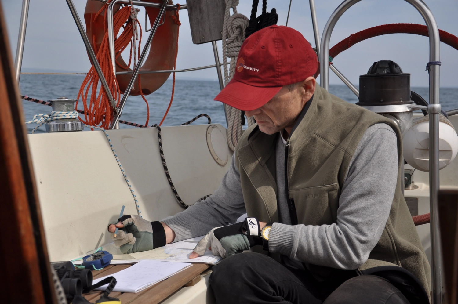 Motorboot-u. Segelschule Ravensburg - Wassersportausbildung und lizenzierung - Ein Mann mit roter Kappe und Weste sitzt auf einem Boot und schreibt auf einem Klemmbrett.