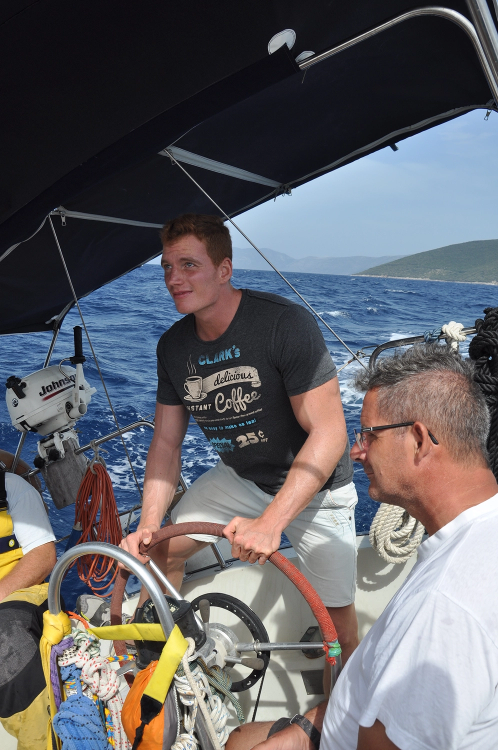 Motorboot-u. Segelschule Ravensburg - Wassersportausbildung und lizenzierung - Zwei Männer auf einem Segelboot; einer steuert, während der andere aufs Wasser hinausschaut.