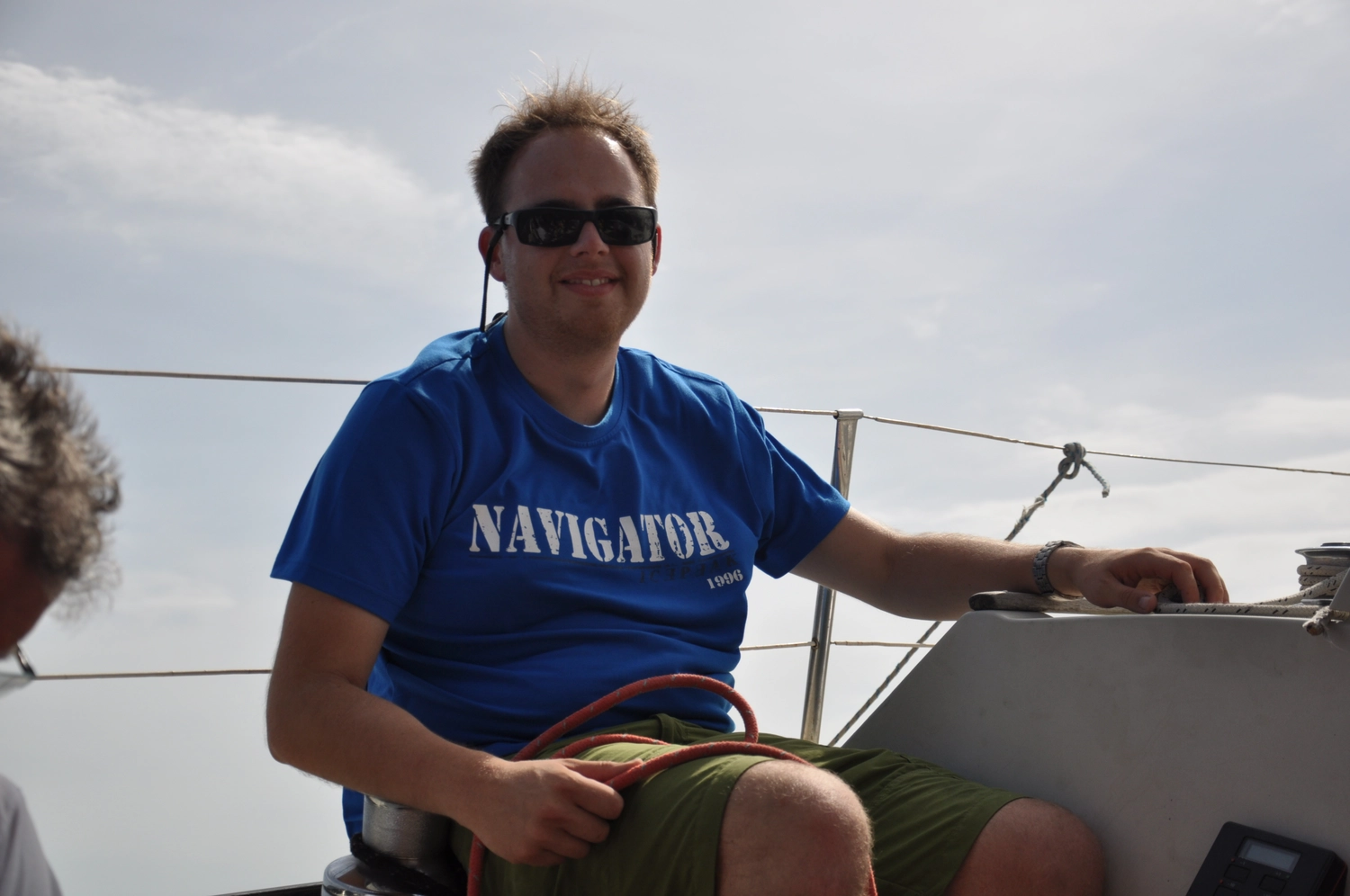 Motorboot-u. Segelschule Ravensburg - Wassersportausbildung und lizenzierung - Ein Mann in einem blauen T-Shirt mit der Aufschrift „NAVIGATOR“ sitzt am Steuer eines Bootes.