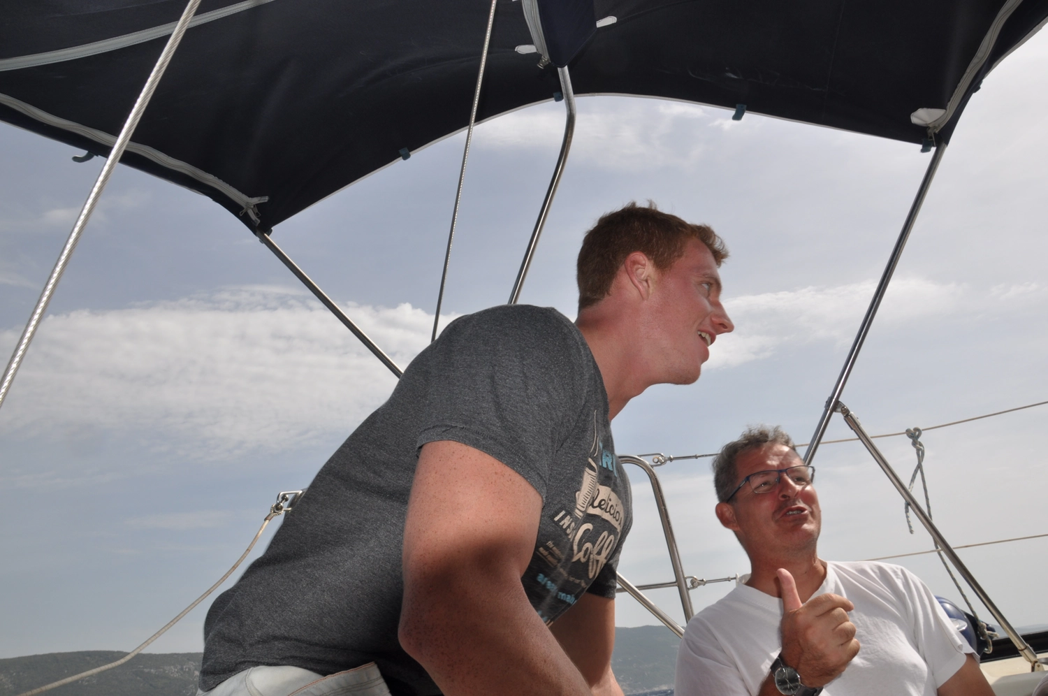 Motorboot-u. Segelschule Ravensburg - Wassersportausbildung und lizenzierung - Zwei Männer unterhalten sich unter einem schwarzen Baldachin auf dem Deck eines Bootes.