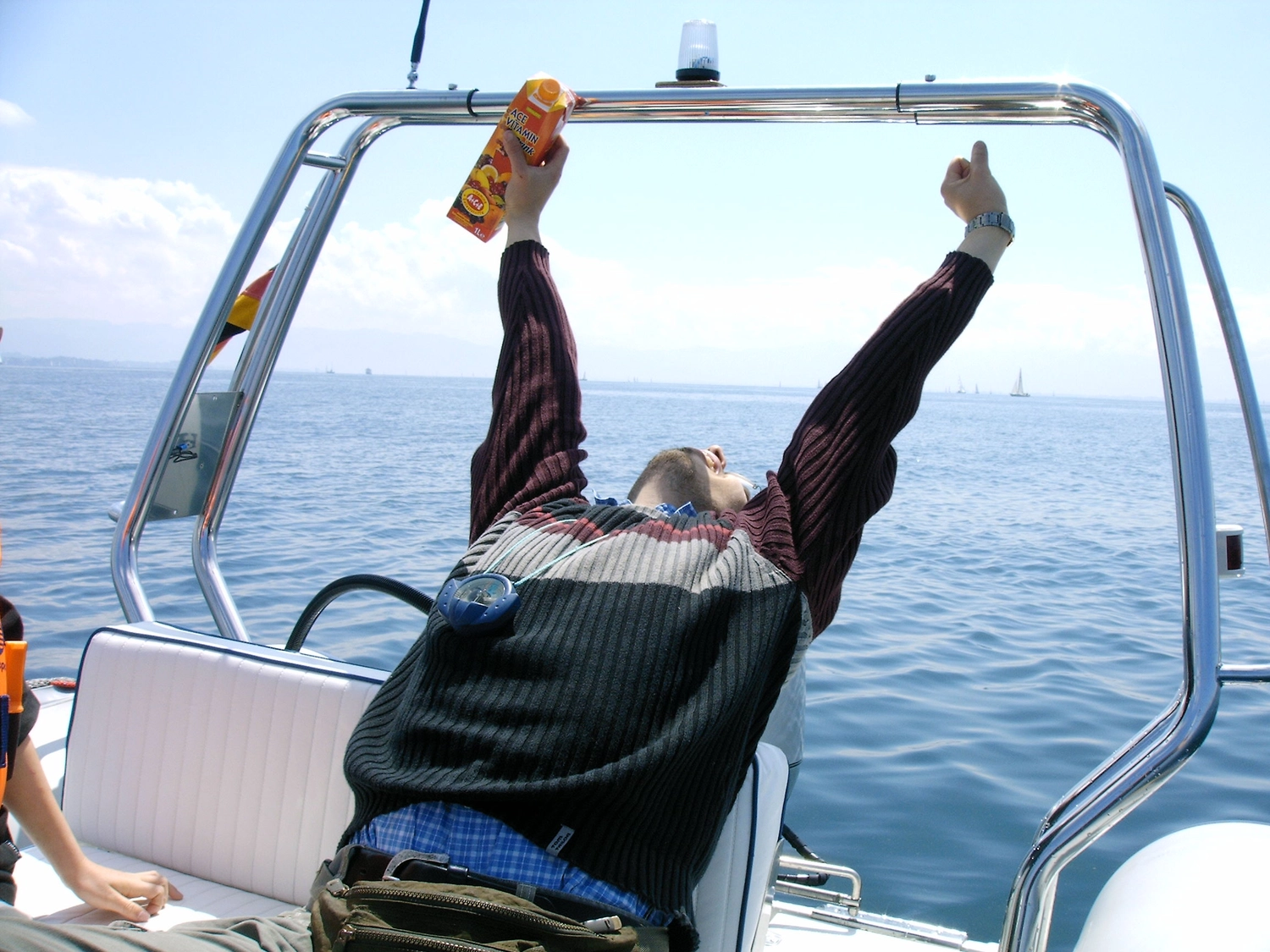 Motorboot-u. Segelschule Ravensburg - Wassersportausbildung und lizenzierung - Eine Person, die aufgeregt die Arme hochreißt, während sie hinten auf einem Boot mitfährt.