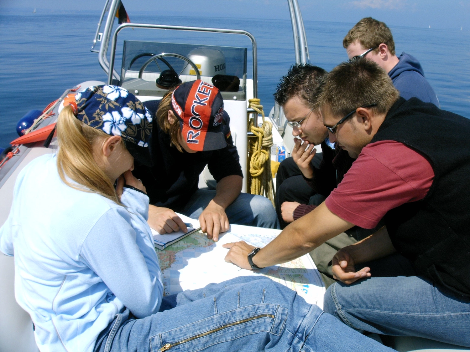 Motorboot-u. Segelschule Ravensburg - Wassersportausbildung und lizenzierung - Eine Gruppe von Menschen saß auf einem Boot um einen Tisch und betrachtete eine Karte oder Dokumente.