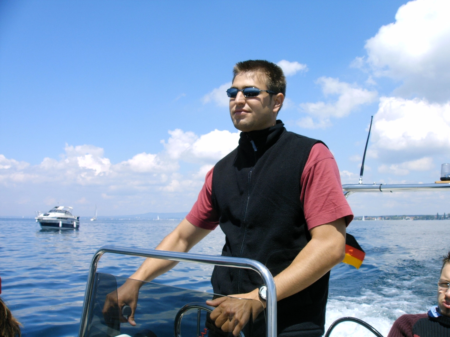 Motorboot-u. Segelschule Ravensburg - Wassersportausbildung und lizenzierung - Ein Mann mit Sonnenbrille und schwarzer Weste steuert souverän ein Motorboot.