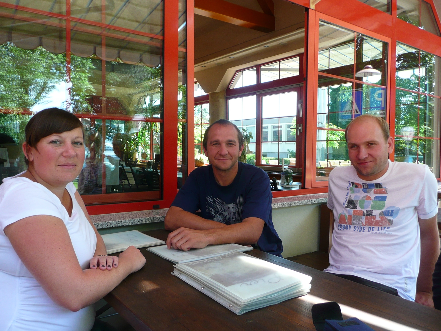 Motorboot-u. Segelschule Ravensburg - Wassersportausbildung und lizenzierung - Drei Personen sitzen an einem Holztisch in einem Restaurant oder einer Hütte mit großen Fenstern.