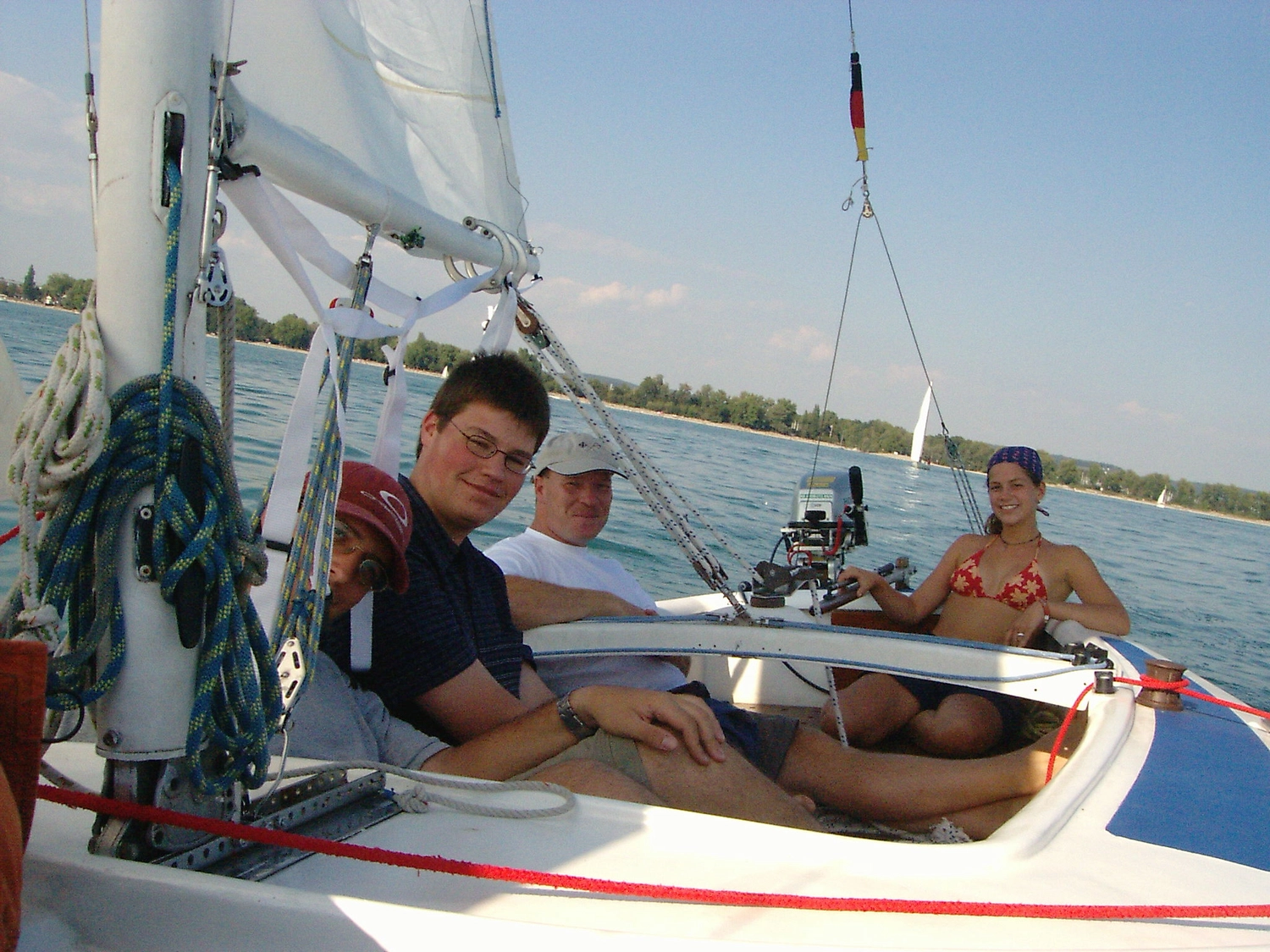 Motorboot-u. Segelschule Ravensburg - Wassersportausbildung und lizenzierung - Mehrere Personen entspannen sich und sonnen sich an Deck eines weißen Segelboots.