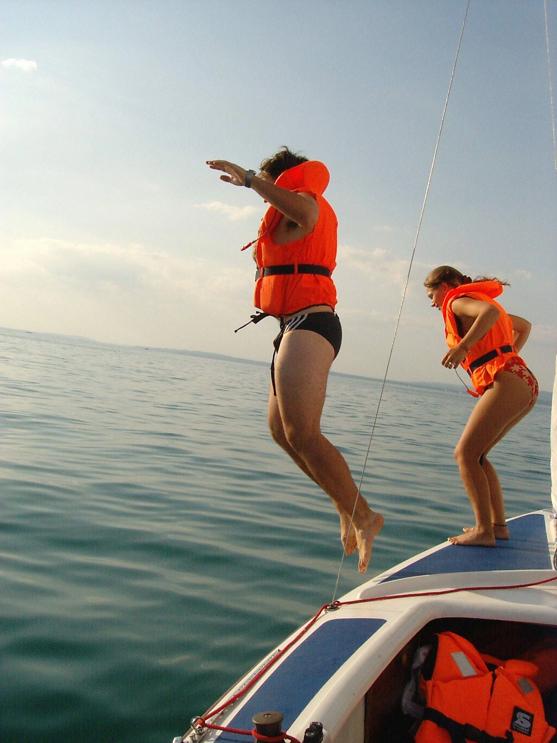 Motorboot-u. Segelschule Ravensburg - Wassersportausbildung und lizenzierung - Zwei Personen in Schwimmwesten springen von der Seite eines Bootes ins Wasser und markieren damit einen Segelkurs für den Bodensee und Binnengewässer.