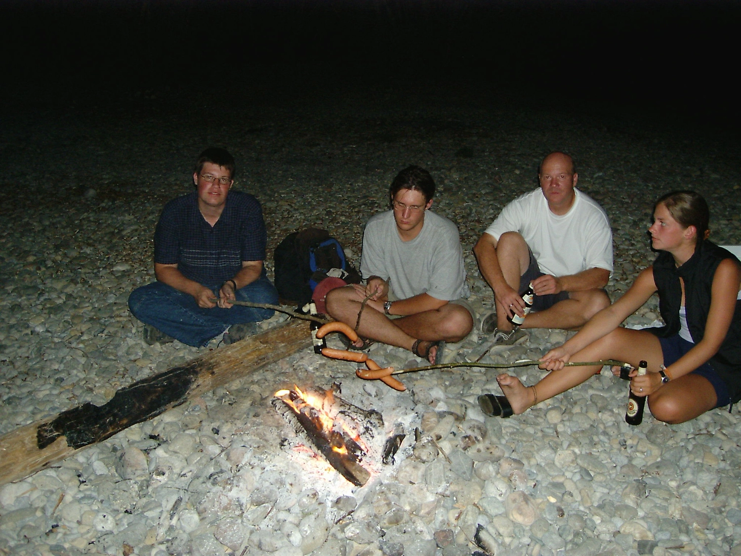 Motorboot-u. Segelschule Ravensburg - Wassersportausbildung und lizenzierung - Vier Personen sitzen nachts an einem Lagerfeuer am Strand.