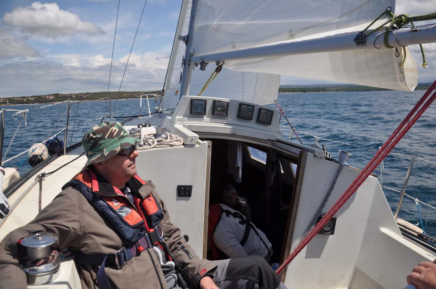 Motorboot-u. Segelschule Ravensburg - Wassersportausbildung und lizenzierung - Ein älterer Mann in einer Schwimmweste entspannt sich an Deck, während das Boot in See sticht.