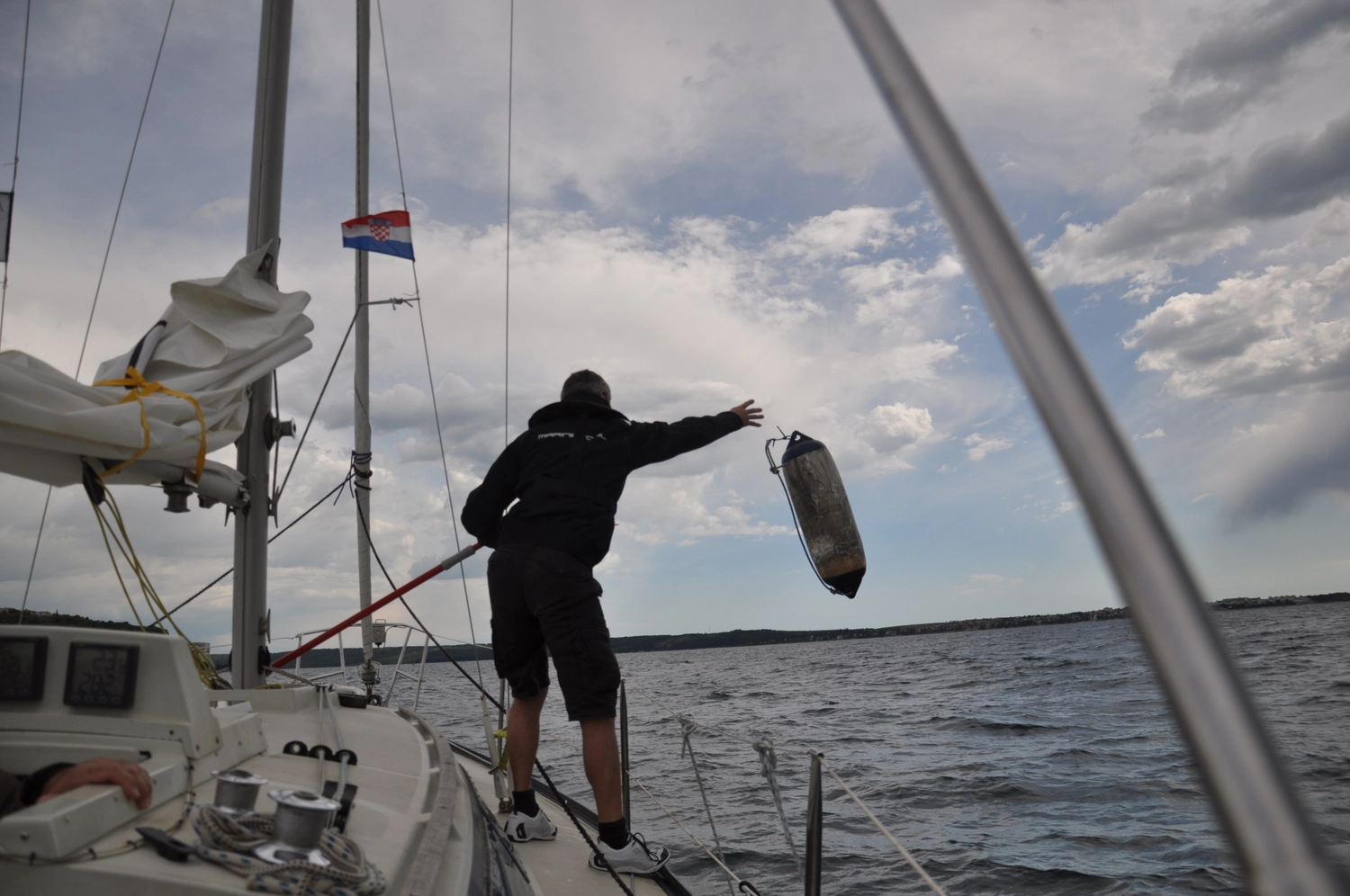 Motorboot-u. Segelschule Ravensburg - Wassersportausbildung und lizenzierung - Eine Person an Deck benutzt einen Bootshaken, um im Wasser nach einer Boje oder einem Fender zu greifen.