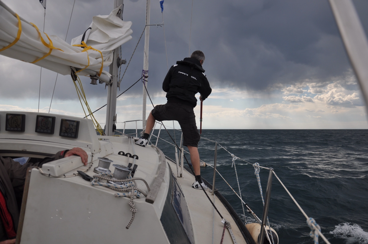 Motorboot-u. Segelschule Ravensburg - Wassersportausbildung und lizenzierung - Ein Besatzungsmitglied steht an Deck in der Nähe des Mastes und blickt auf ein bewölktes Meer hinaus.