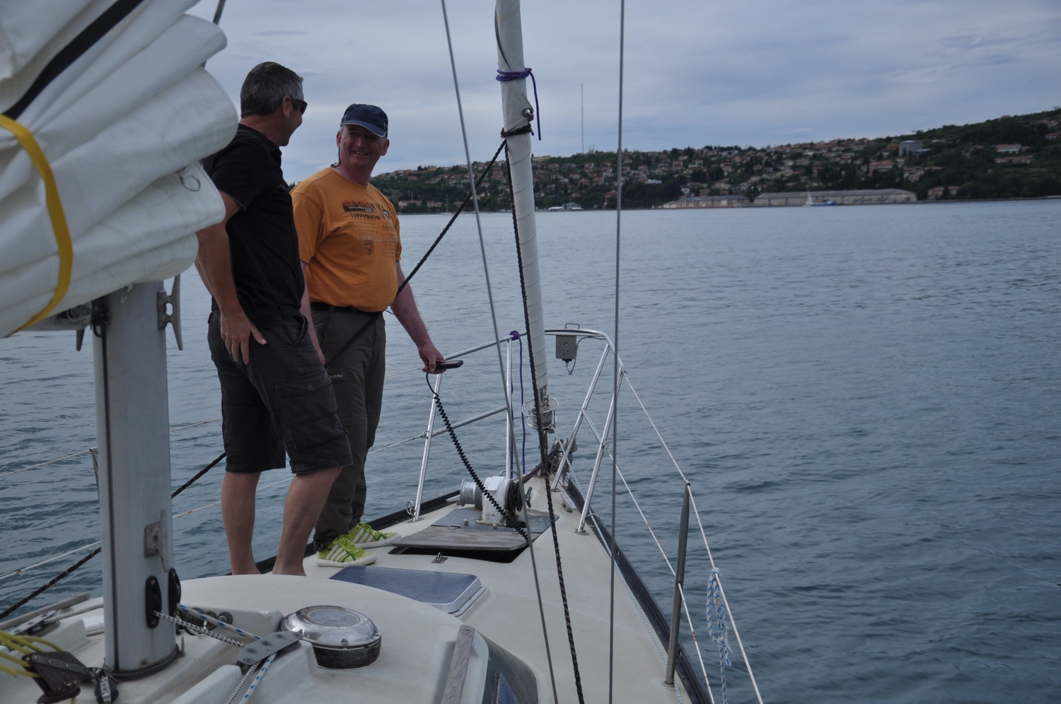 Motorboot-u. Segelschule Ravensburg - Wassersportausbildung und lizenzierung - Ein Mann steht auf dem Deck eines weißen Motorboots in der Nähe eines Ufers.
