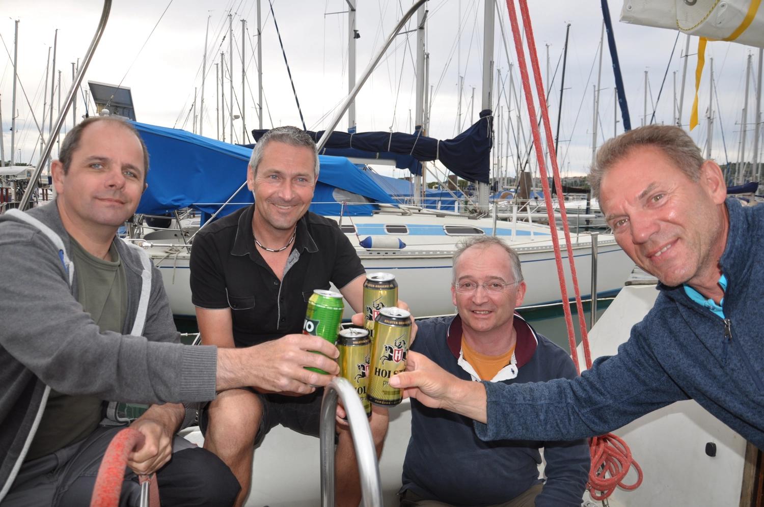 Motorboot-u. Segelschule Ravensburg - Wassersportausbildung und lizenzierung - Vier Männer sitzen zusammen an Deck, lächeln und erheben ihre Getränke zum Anstoßen.