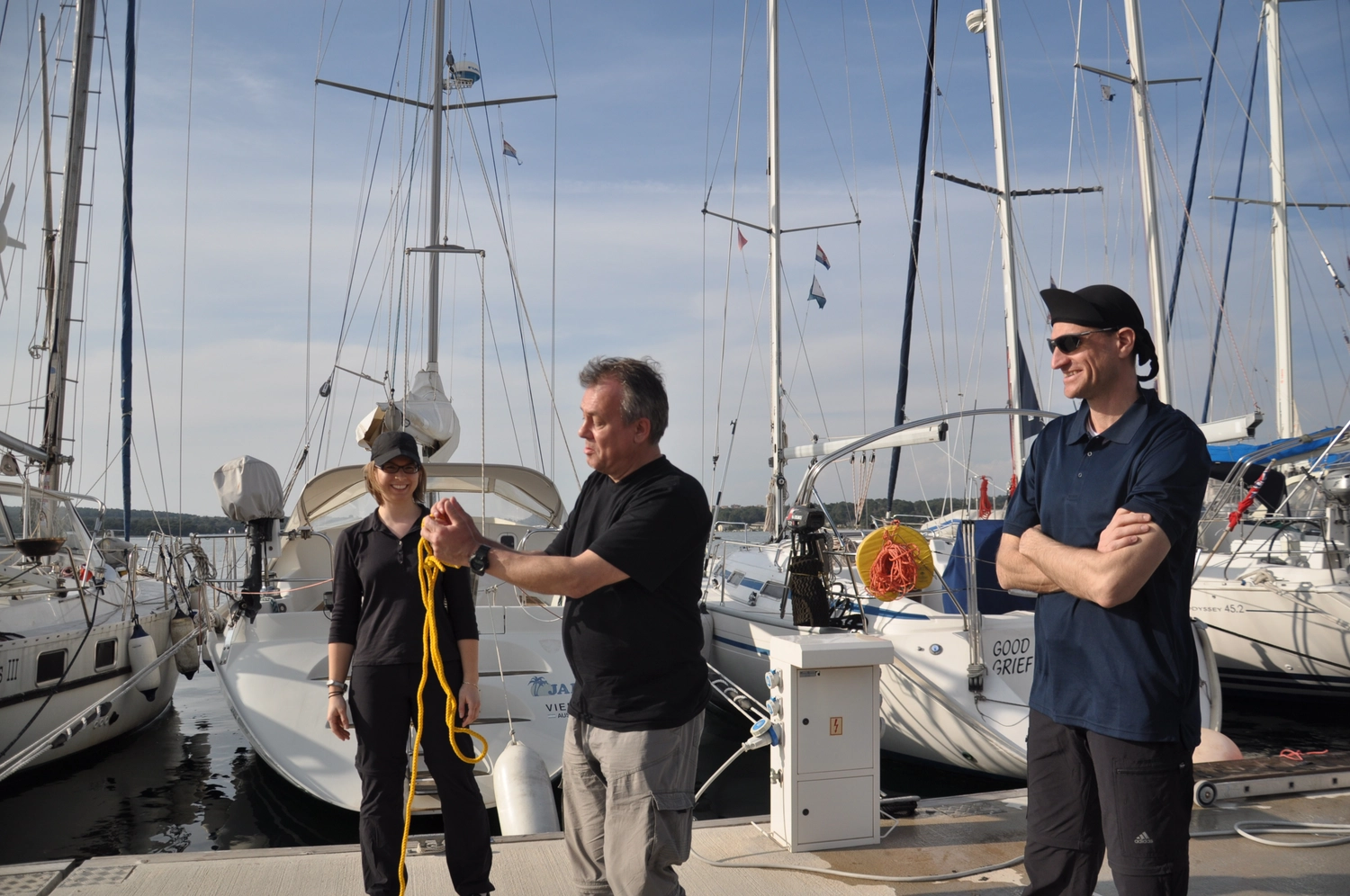 Motorboot-u. Segelschule Ravensburg - Wassersportausbildung und lizenzierung - Drei Personen stehen auf einem Steg neben Segelbooten und bereiten sich auf eine Fahrt vor.
