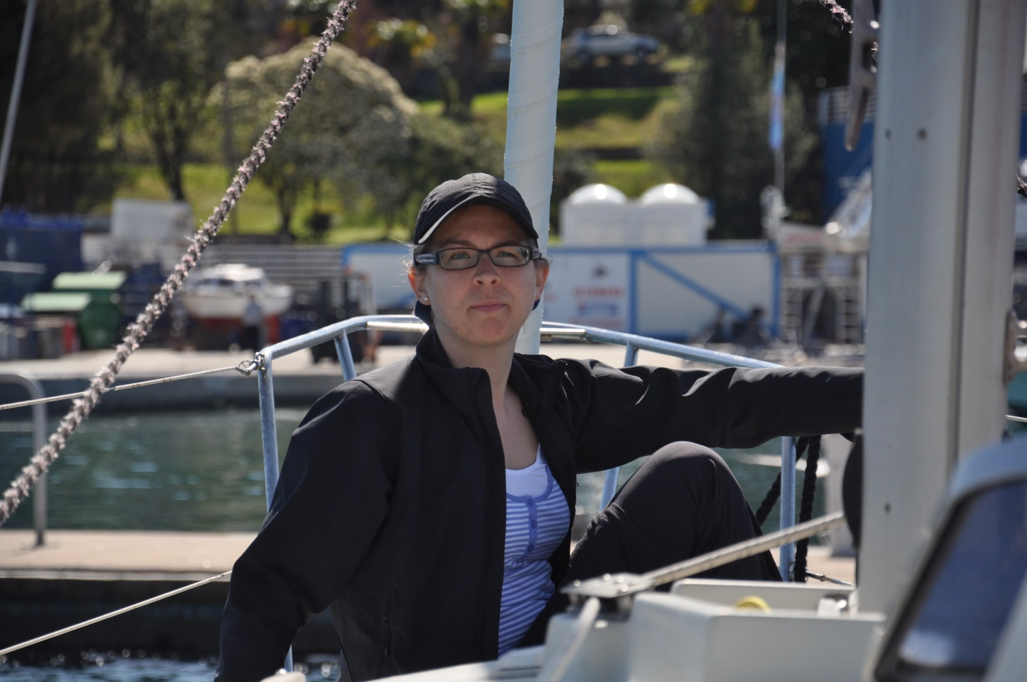 Motorboot-u. Segelschule Ravensburg - Wassersportausbildung und lizenzierung - Eine Frau in schwarzer Jacke und Baseballkappe posiert auf einem Boot.