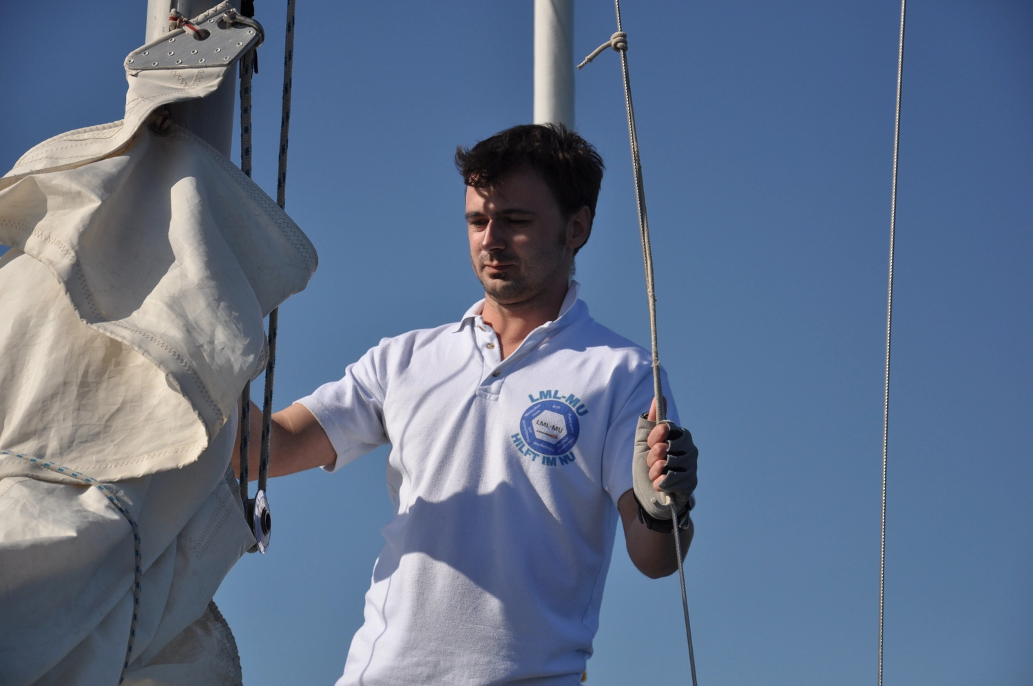 Motorboot-u. Segelschule Ravensburg - Wassersportausbildung und lizenzierung - Ein Mann in einem weißen Poloshirt justiert ein Segel an einem Boot.
